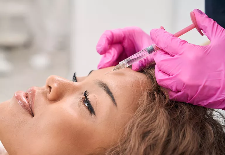 Clinician administering a Botox injection to a client's forehead.